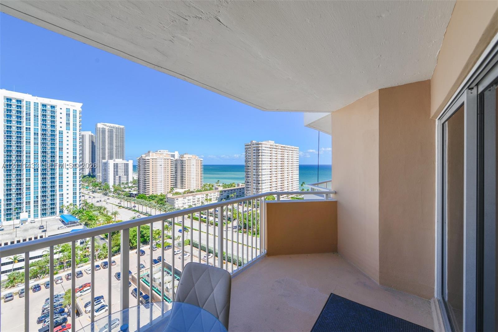 Covered balcony featuring metal railing and concrete flooring with coastal and city skyline scenery