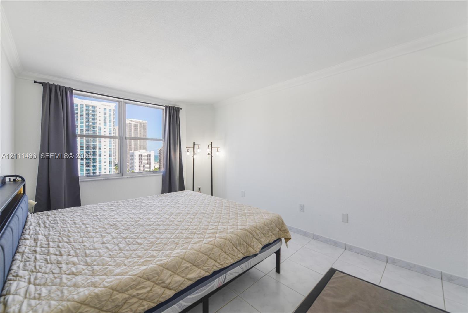 Bright room featuring large windows, neutral tile flooring, and crown molding