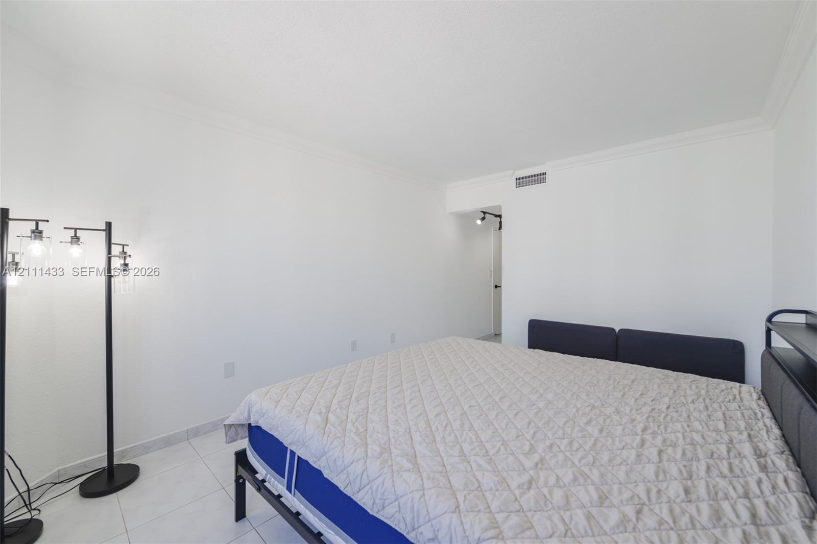 Neutral interior space featuring polished tile flooring, crisp white walls, crown molding, and recessed lighting