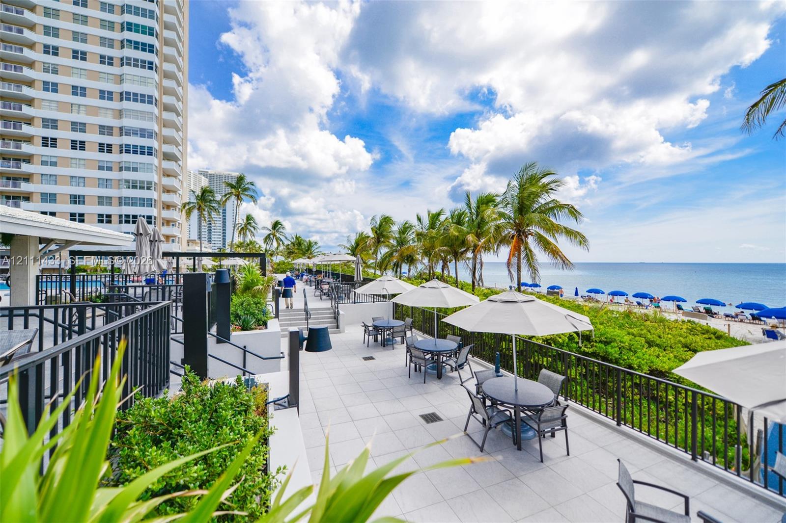 Elevated concrete terrace featuring tiered levels, black metal perimeter fencing, built-in structural planters, and direct coastal frontage