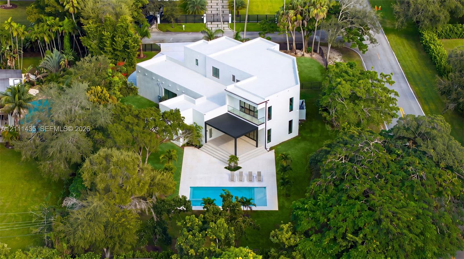 Multi-level residence featuring a flat roofline, minimalist white exterior, covered rear terrace, private swimming pool, and stone pool deck