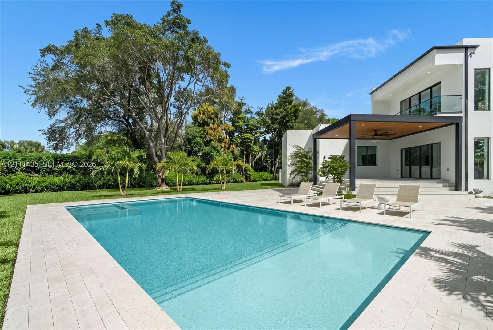 Modern exterior featuring a swimming pool, integrated spa, stone-paver decking, and a covered lanai with a wood-finished ceiling