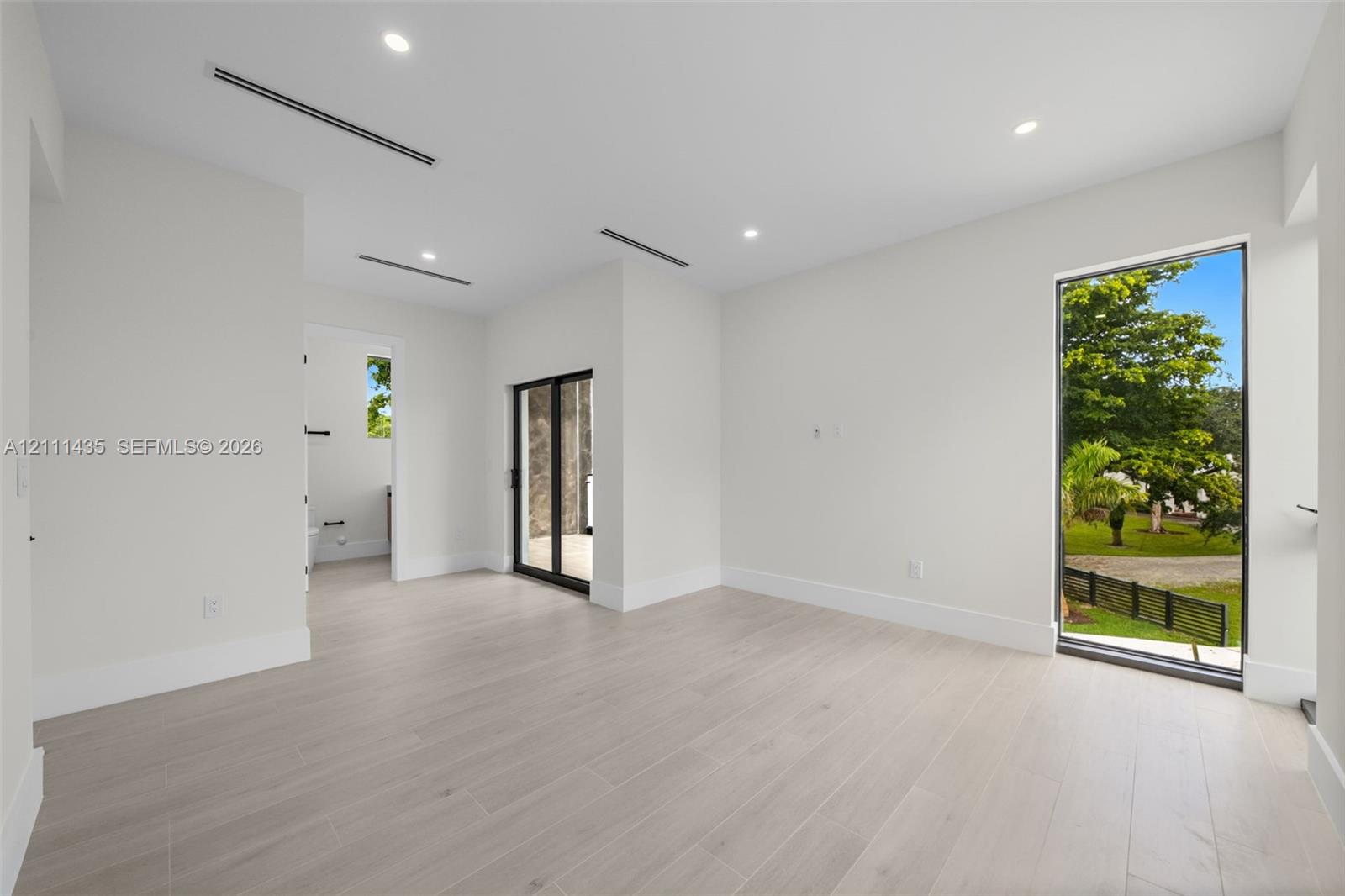 Neutral-toned wood-finish flooring, recessed lighting, floor-to-ceiling window, and sliding glass door