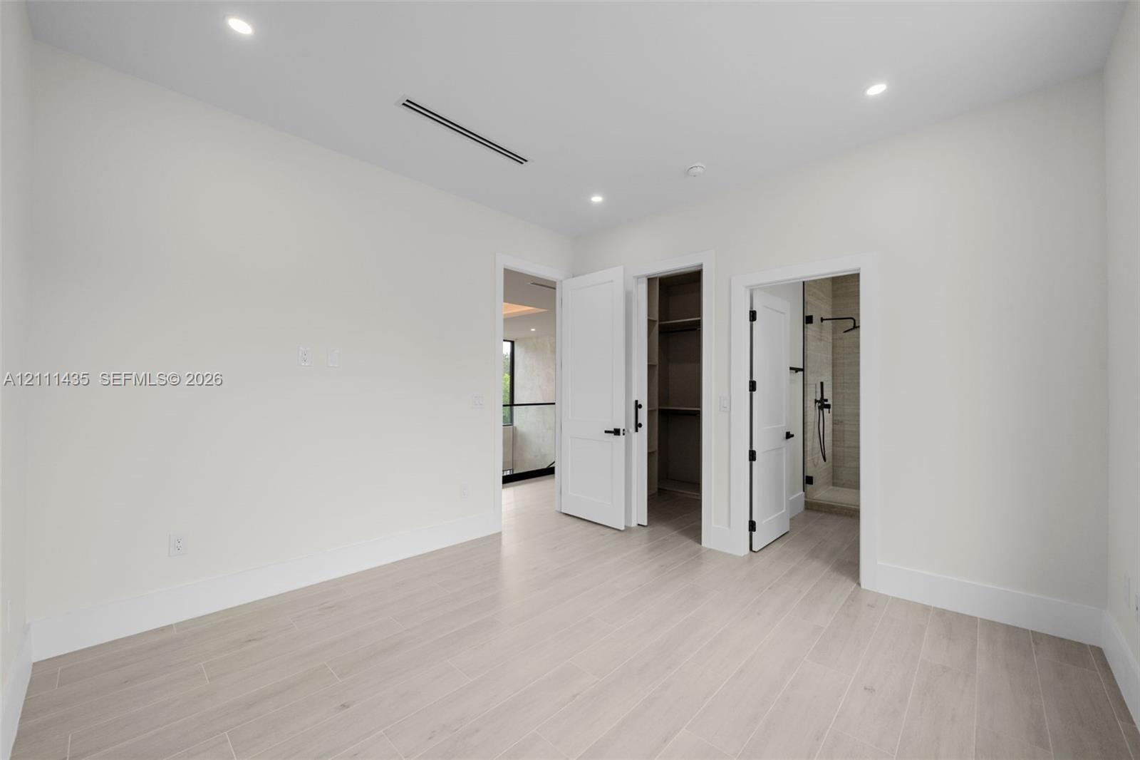Neutral room with wood-finish flooring, recessed lighting, built-in closet shelving, and shaker-style interior doors