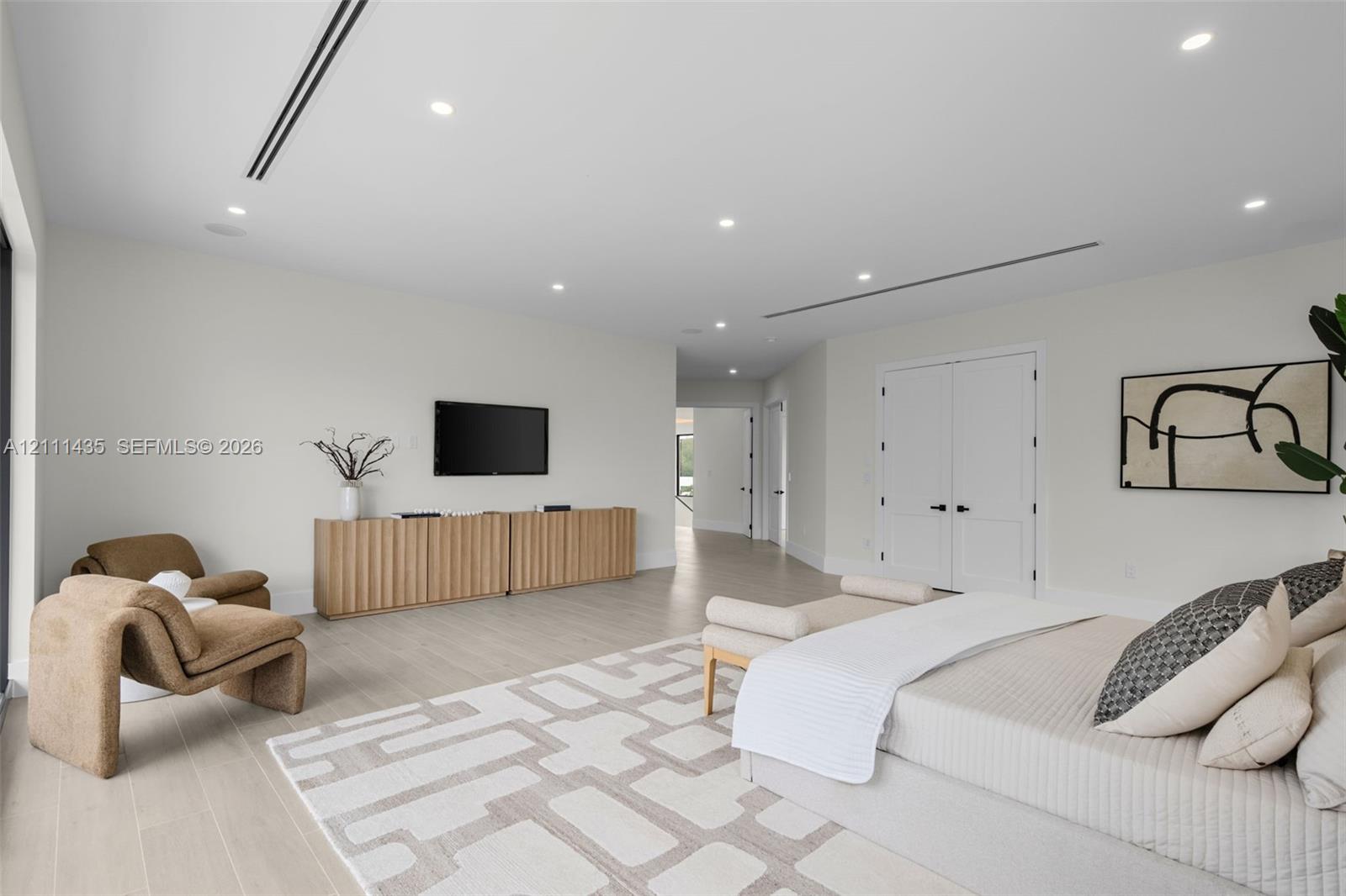 Neutral-toned interior featuring wood-finish flooring, recessed LED lighting, integrated linear air vents, and double-panel doors with matte black hardware