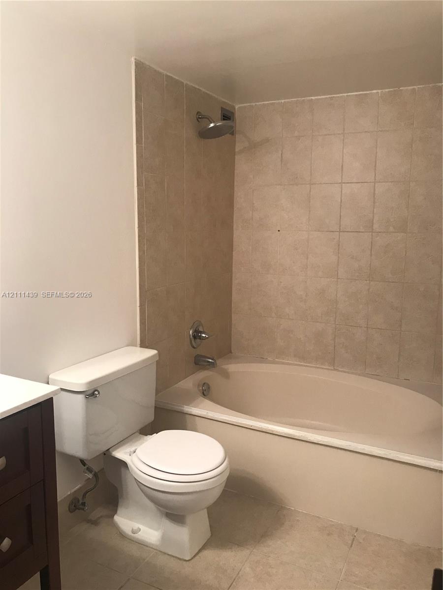 Bathroom featuring a soaking tub, wall-mounted shower head, ceramic tile surround, and neutral floor tile