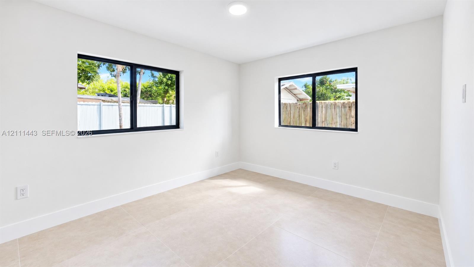 Neutral-toned oversized tile flooring, dual-aspect windows with black frames, and recessed lighting
