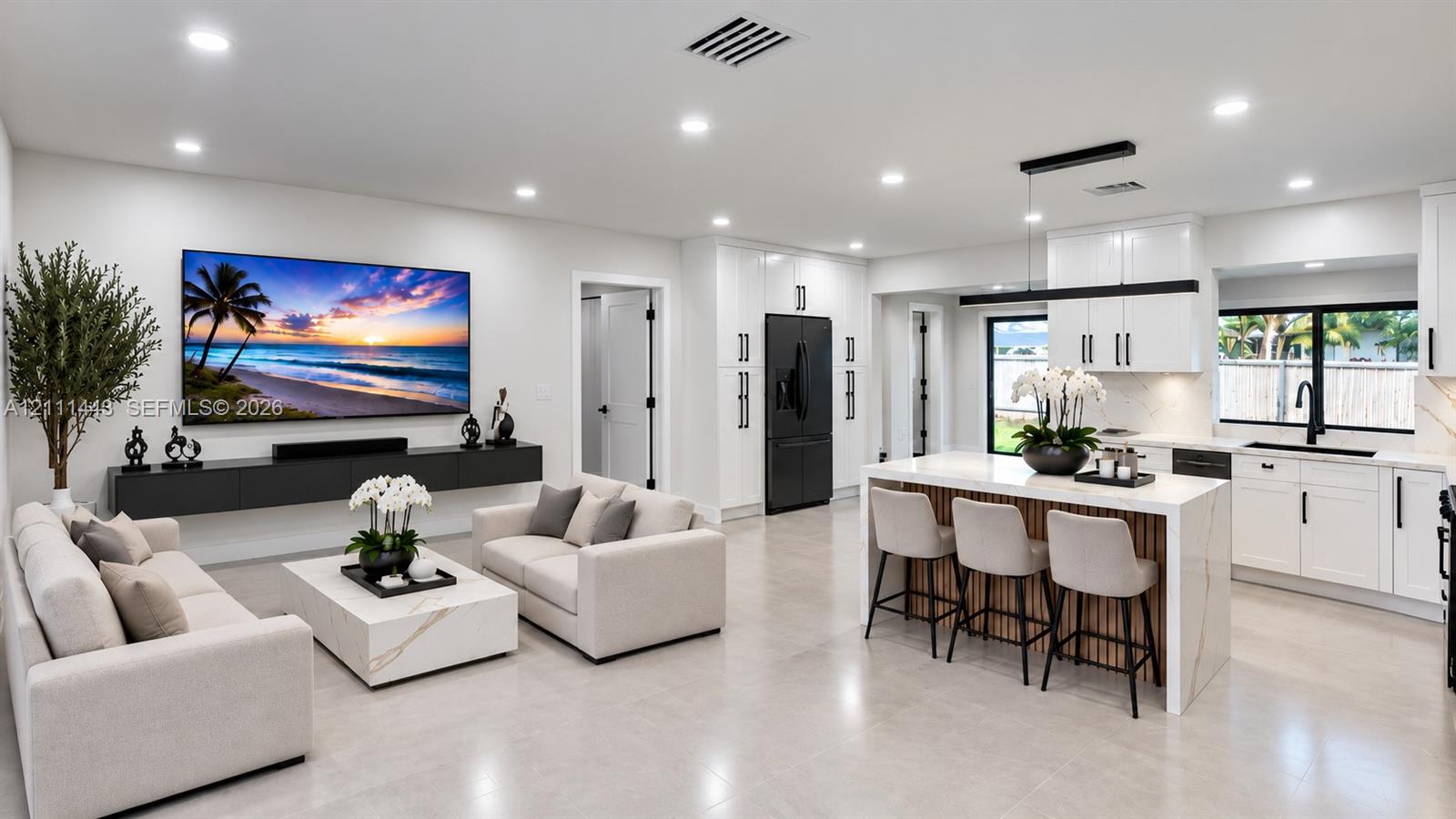 Digitally Staged- Open-concept living space featuring high-gloss white cabinetry, a kitchen island with stone-finish waterfall countertops, matte black hardware, tile flooring, and a wall-mounted floating media console