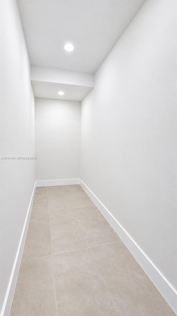 Neutral-toned ceramic floor tiling paired with minimalist white walls and recessed ceiling lighting