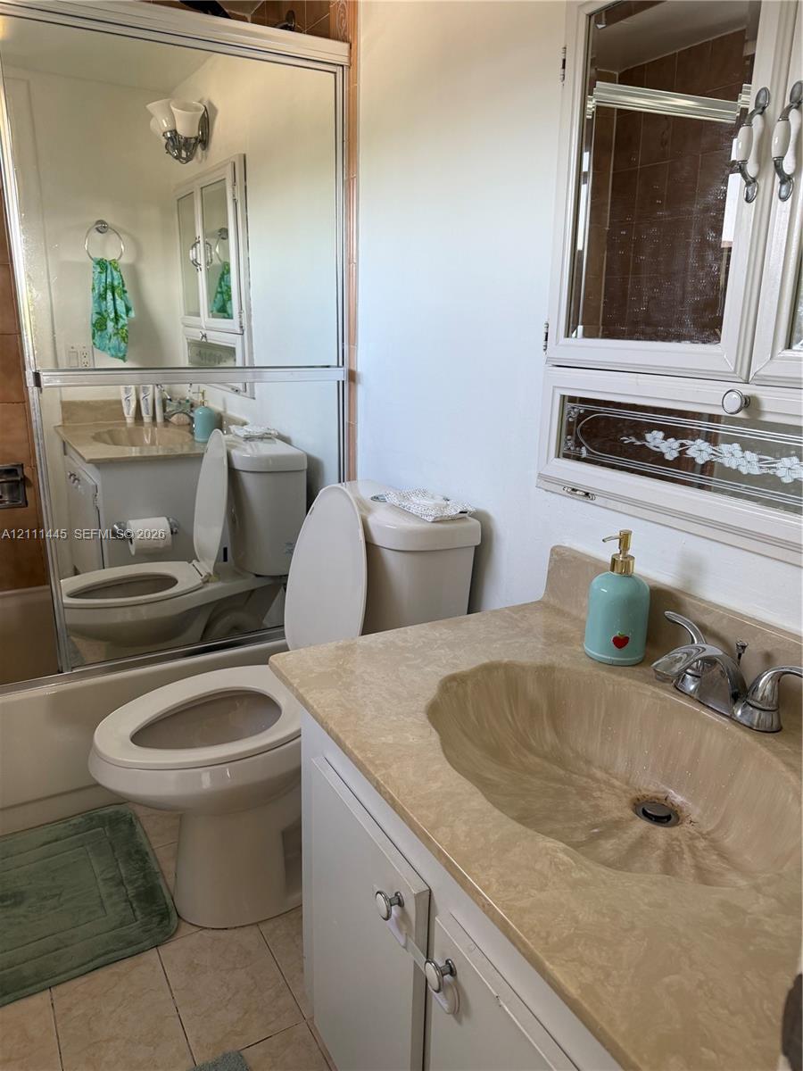 Vanity featuring an integrated molded sink, stone-finish countertop, and chrome dual-handle faucet, complemented by a large wall-mounted mirror and a built-in recessed medicine cabinet with decorative glass detailing