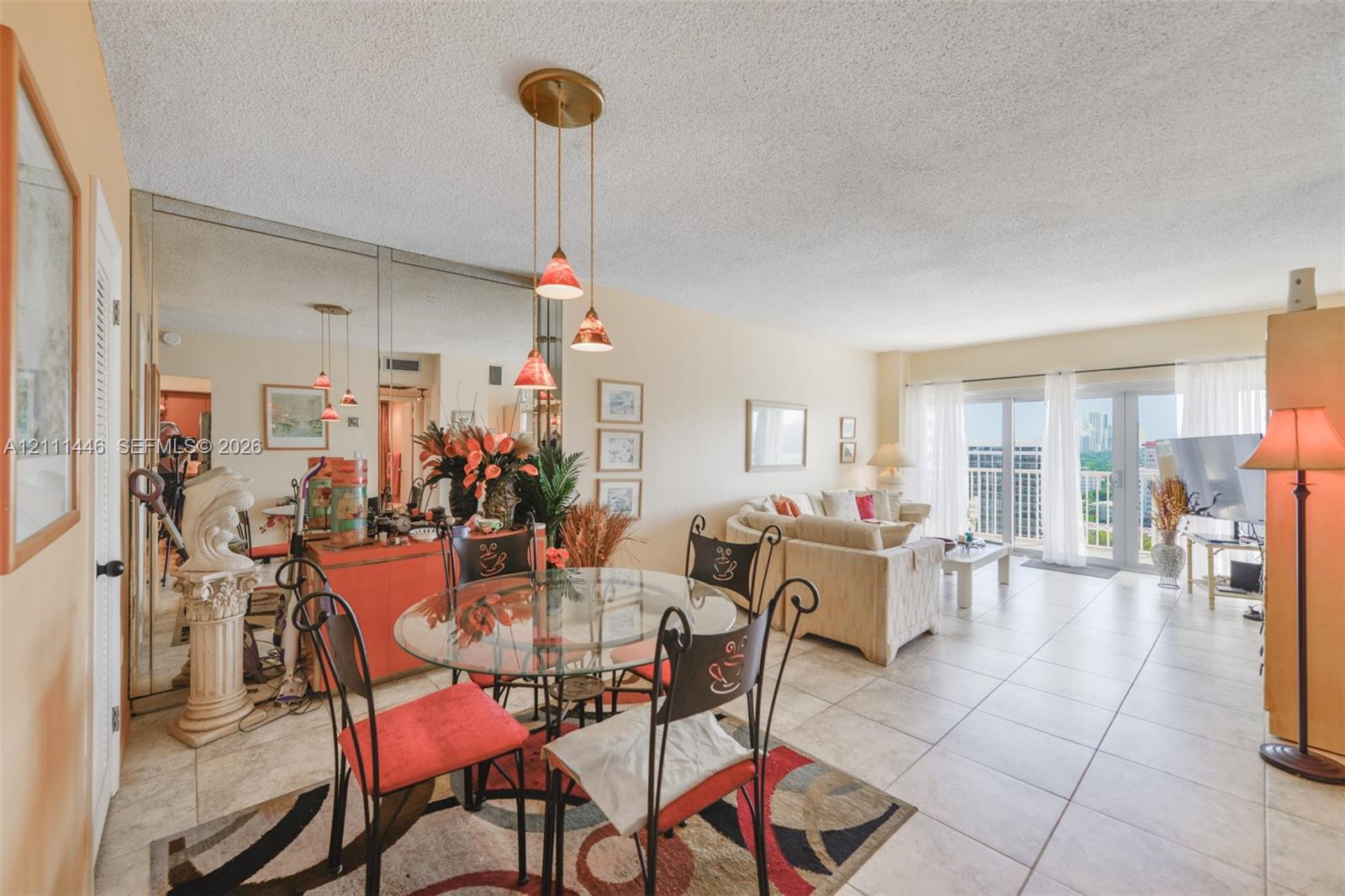 Ceramic tile flooring, full-length wall mirrors, three-light hanging pendant fixture, and sliding glass doors with balcony access