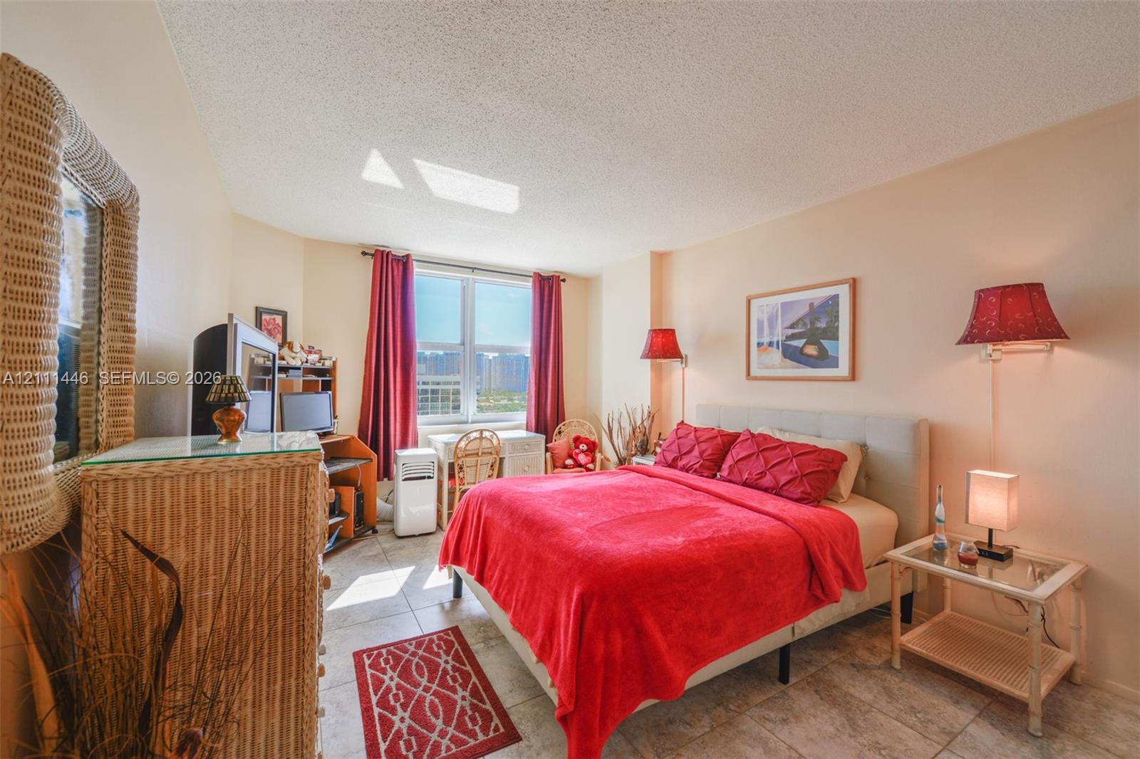 Bedroom featuring tile flooring, a large window providing natural light, and dual wall-mounted light fixtures