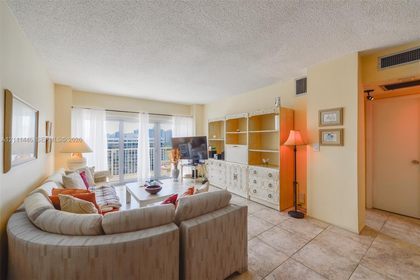 Living area featuring large-format ceramic tile flooring, built-in floor-to-ceiling cabinetry, and expansive glass sliding doors providing exterior access