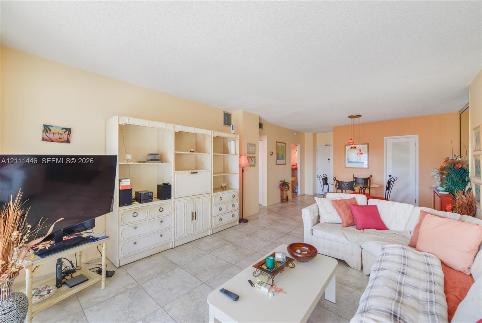 Living area featuring large-format ceramic tile flooring and floor-to-ceiling built-in shelving