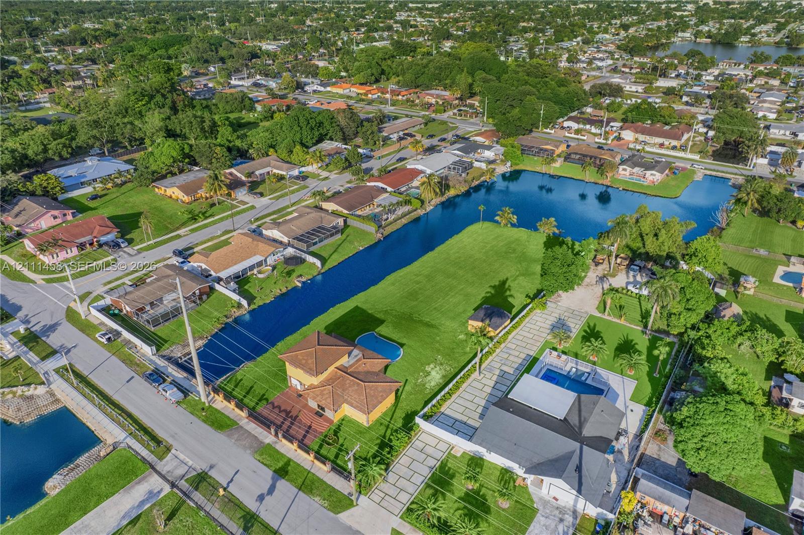 Waterfront lot featuring a sprawling lawn, a private swimming pool, and an expansive paver driveway