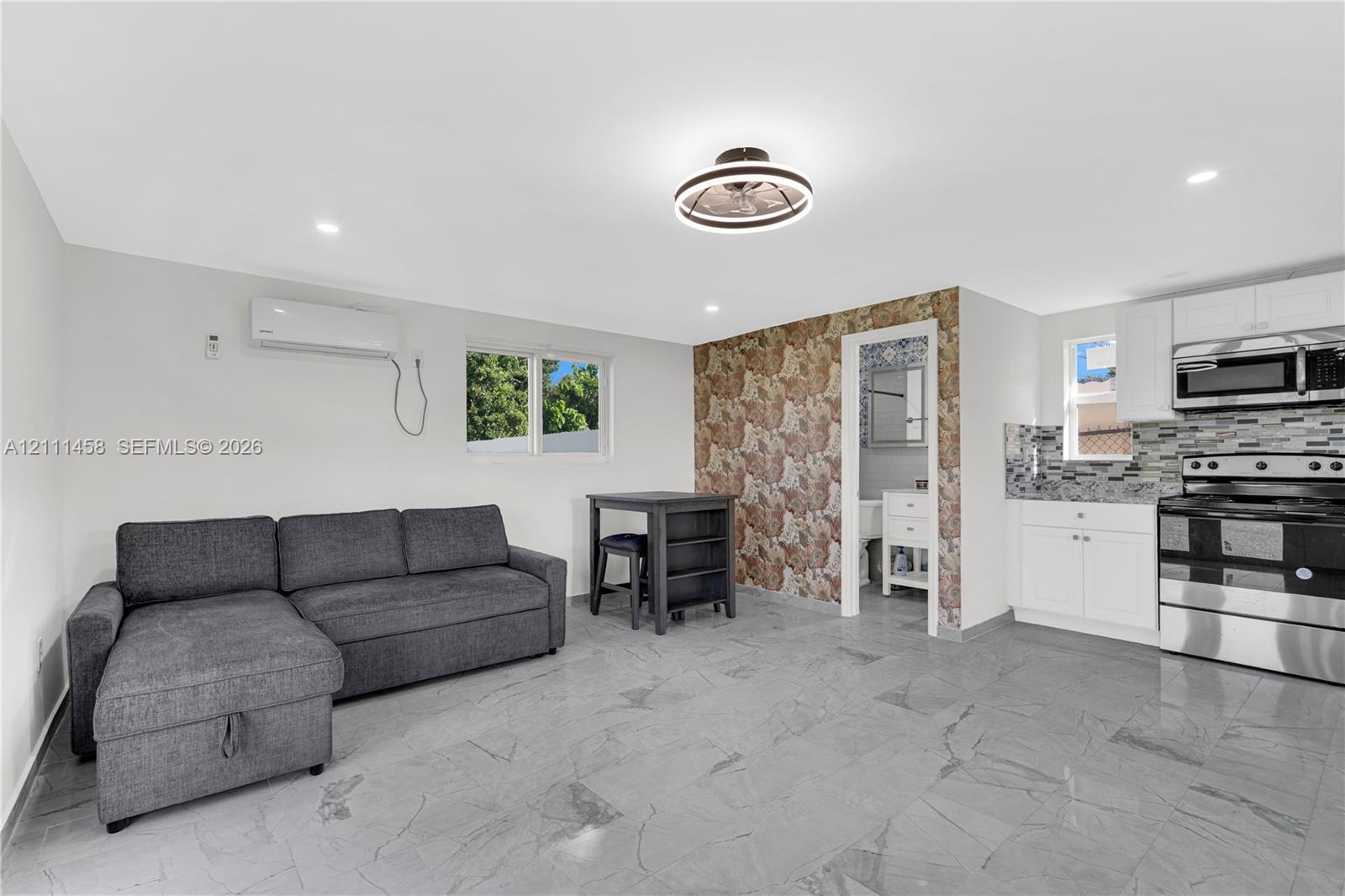 Interior featuring a built-in kitchen with white cabinetry and stainless steel appliances