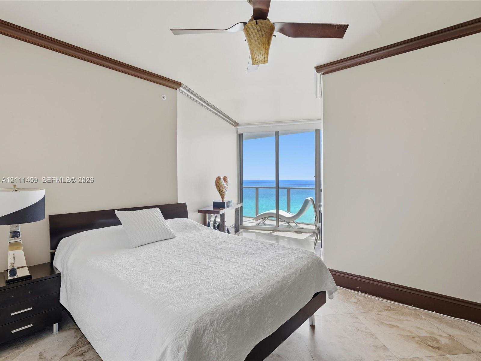 Stone flooring, expansive sliding glass doors, ceiling fan with light fixture, and crown molding