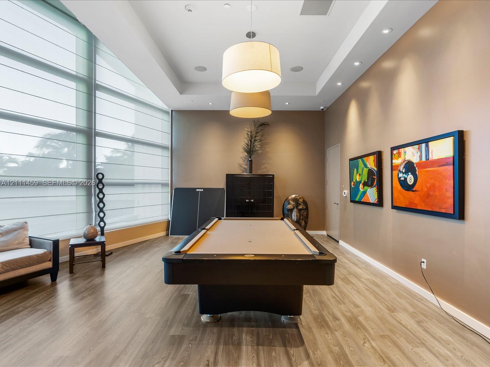 Floor-to-ceiling windows with integrated shade systems, wood-finish flooring, recessed lighting, and tiered drum pendant fixtures