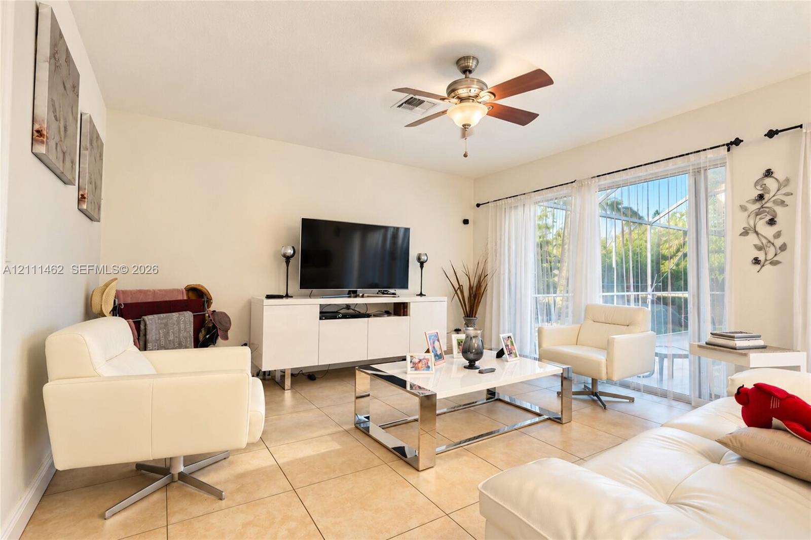 Living area featuring tile flooring, a central ceiling fan with integrated lighting, and large sliding glass doors
