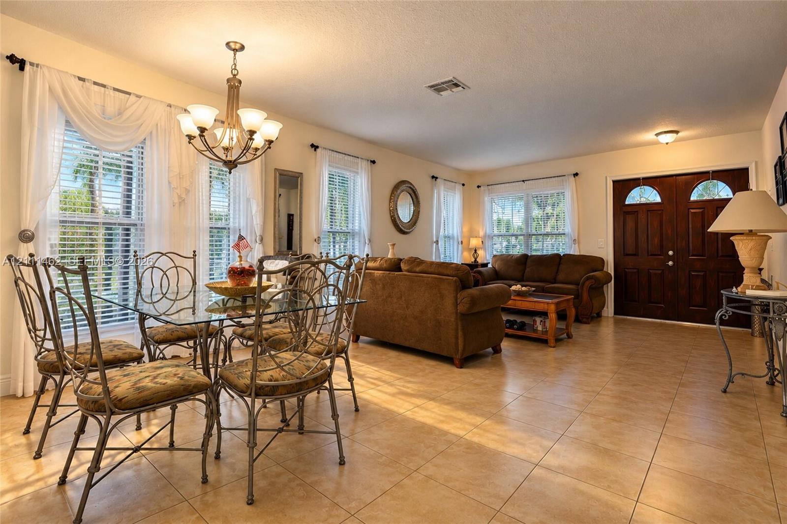 Open-concept main area featuring large-format ceramic tile flooring, double-door entry, and a multi-arm chandelier Open-concept main area featuring large-format ceramic tile flooring, double-door entry, and a multi-arm chandelier