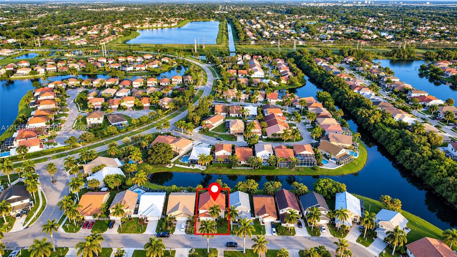 Aerial perspective featuring a multi-pitched tile roof, palm tree landscaping, and a water-front location within a residential community Aerial perspective featuring a multi-pitched tile roof, palm tree landscaping, and a water-front location within a residential community