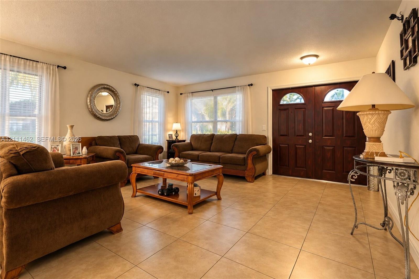 Spacious room featuring tile flooring, double entry doors with glass inserts, and multiple large windows Spacious room featuring tile flooring, double entry doors with glass inserts, and multiple large windows