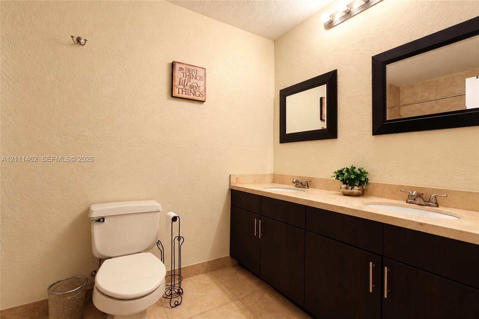 Dual-sink vanity with dark cabinetry, light-toned countertop, and rectangular wall-mounted mirrors