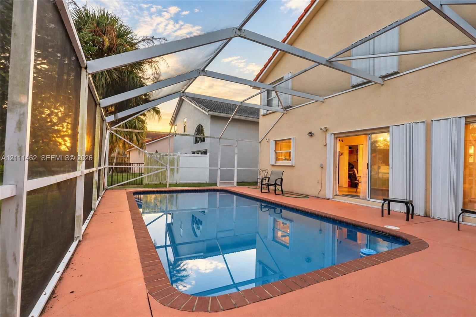 Screened-in patio featuring a rectangular swimming pool with brick coping and a painted concrete deck Screened-in patio featuring a rectangular swimming pool with brick coping and a painted concrete deck
