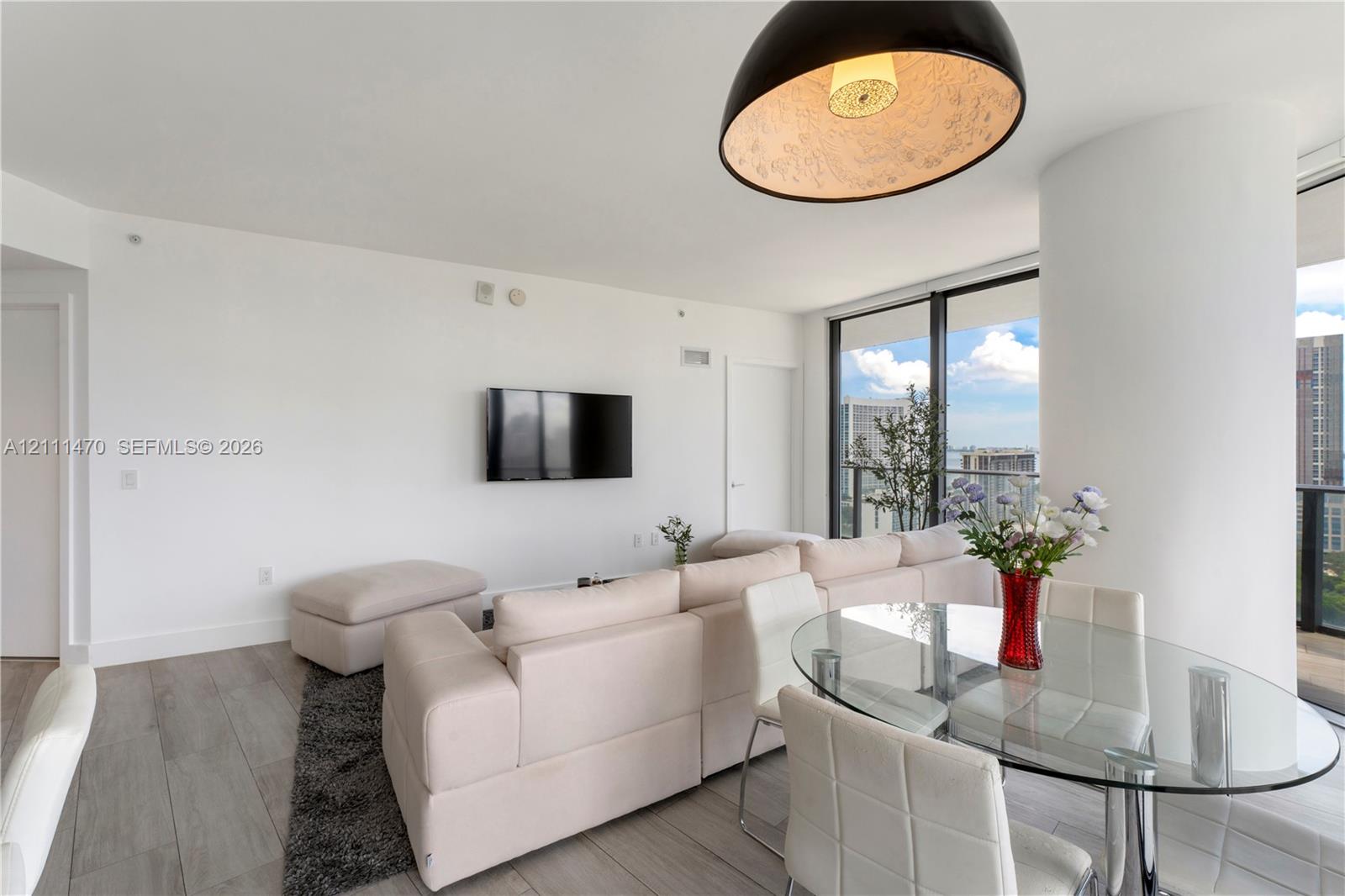 Living area featuring wood-finish flooring, floor-to-ceiling windows, a structural column, and a dome-shaped pendant light fixture
