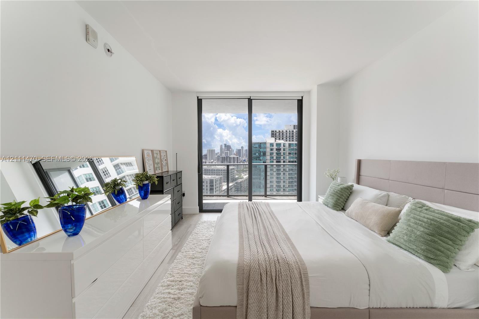 Neutral-toned room featuring floor-to-ceiling sliding glass doors, a balcony with a metal railing, and light-toned flooring