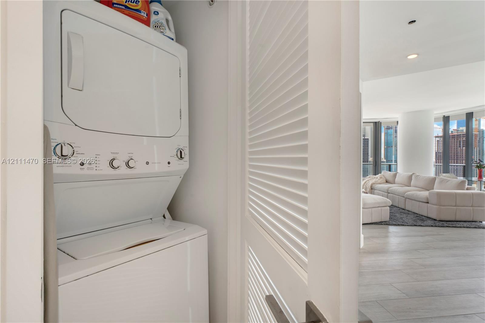 Stacked laundry unit enclosed by white louvered doors