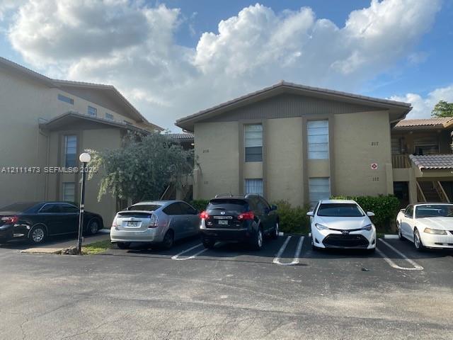 Multi-story exterior featuring a textured stucco finish, low-pitched rooflines, and assigned asphalt parking