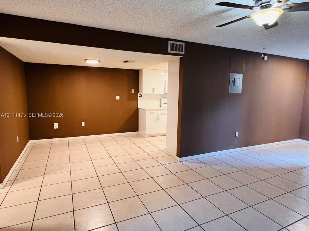 Ceramic tile flooring, white cabinetry, ceiling fan with integrated light fixture, and textured ceilings