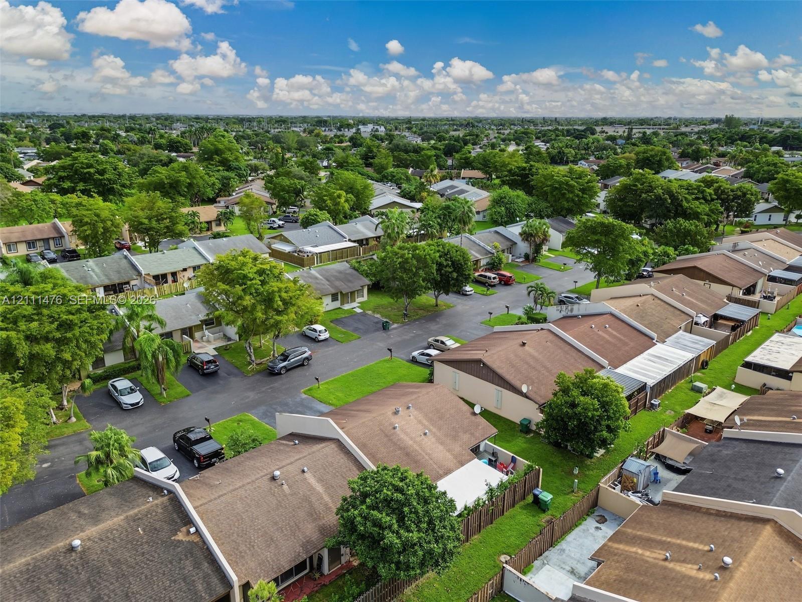 Aerial perspective featuring dense mature tree canopies, paved street grid, and manicured green spaces