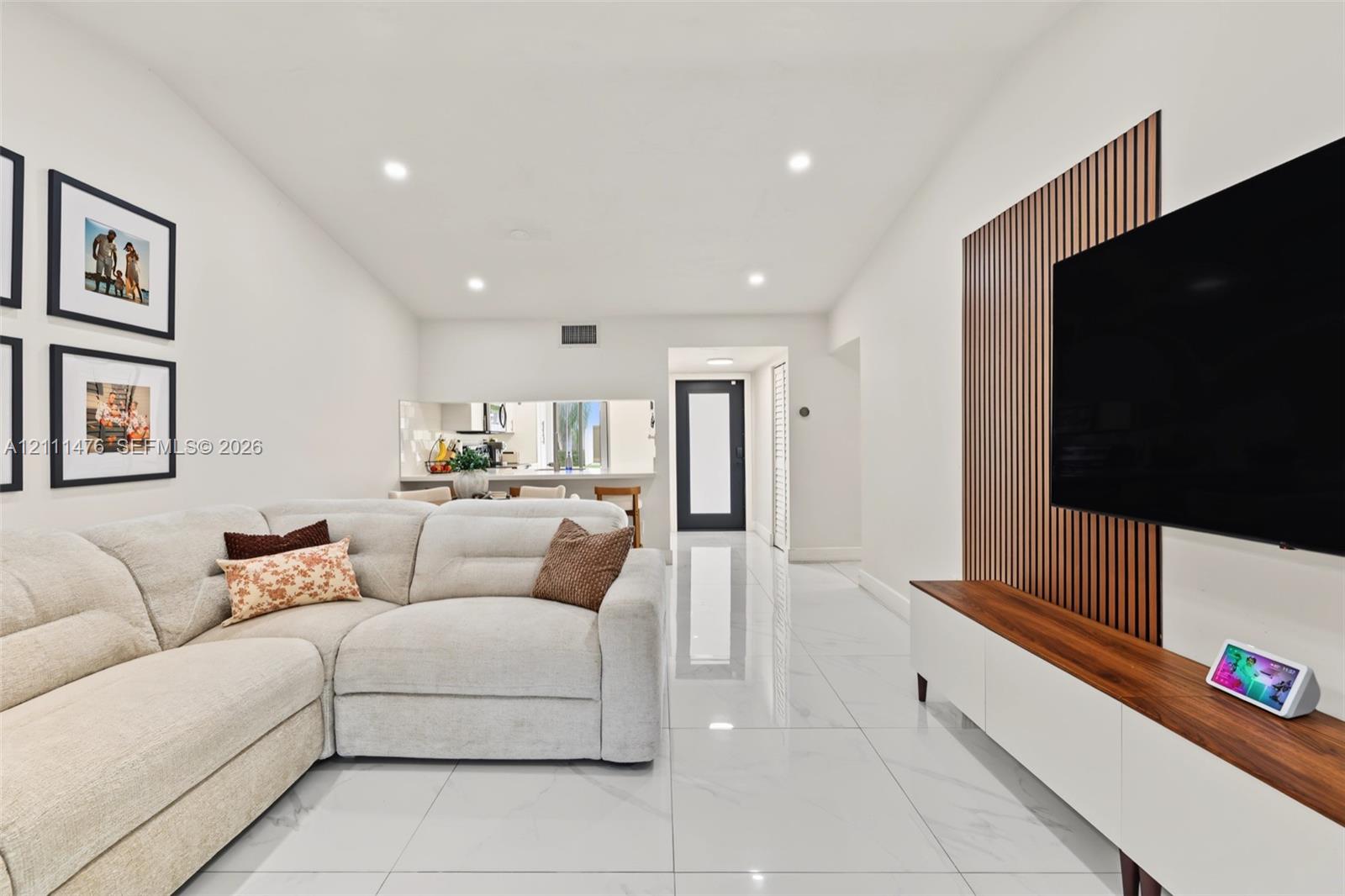 Interior featuring large-format tile flooring, recessed lighting, and a vertical wood-slat accent wall