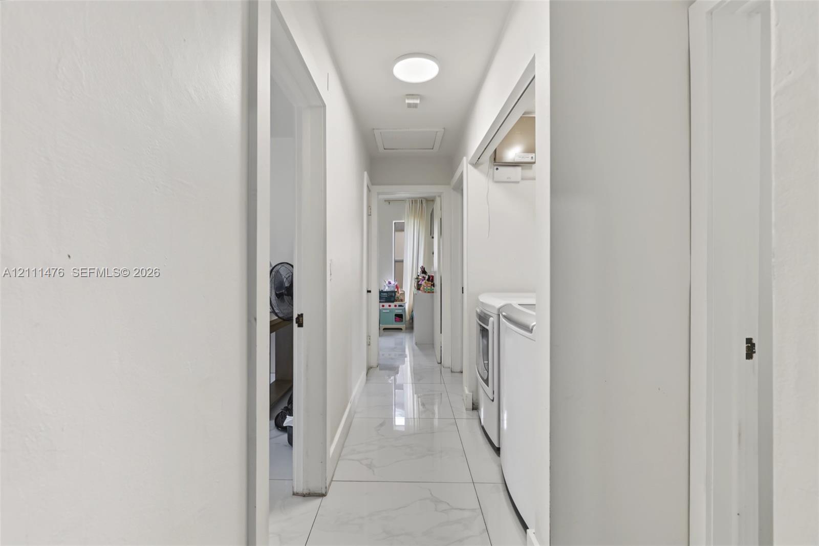 Interior hallway featuring large-format stone-look tile flooring and a flush-mount circular ceiling light