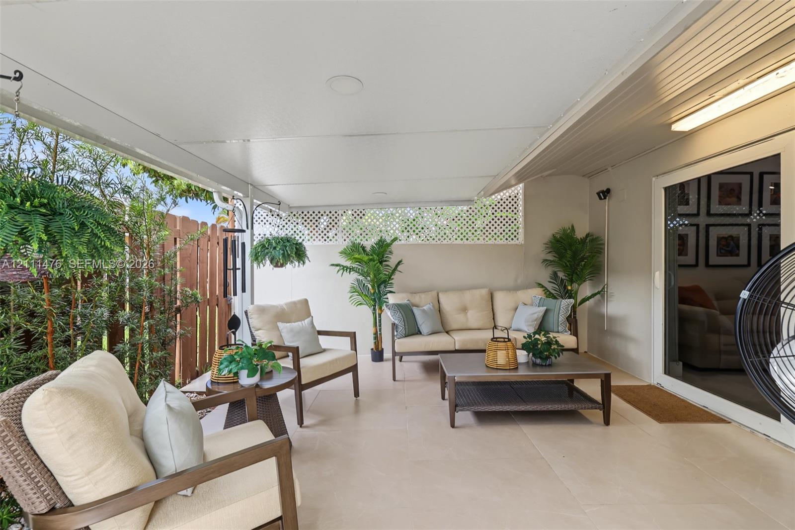 Covered patio featuring tile flooring, lattice-work privacy screen, and glass sliding door access