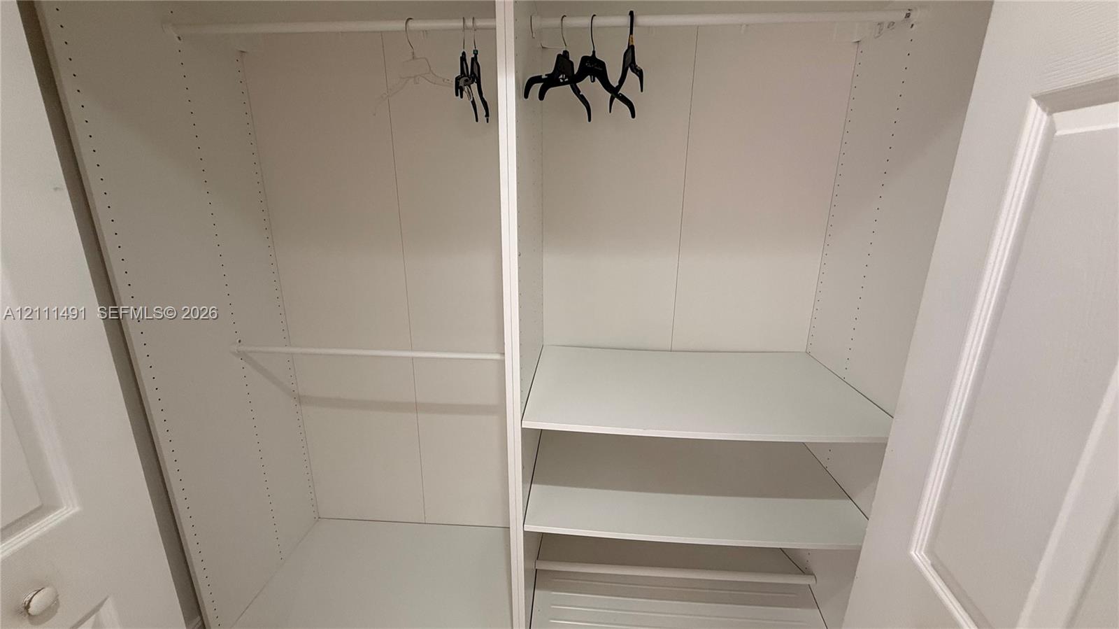 Built-in closet featuring white interior shelving, dual hanging rods, and adjustable shelving tracks