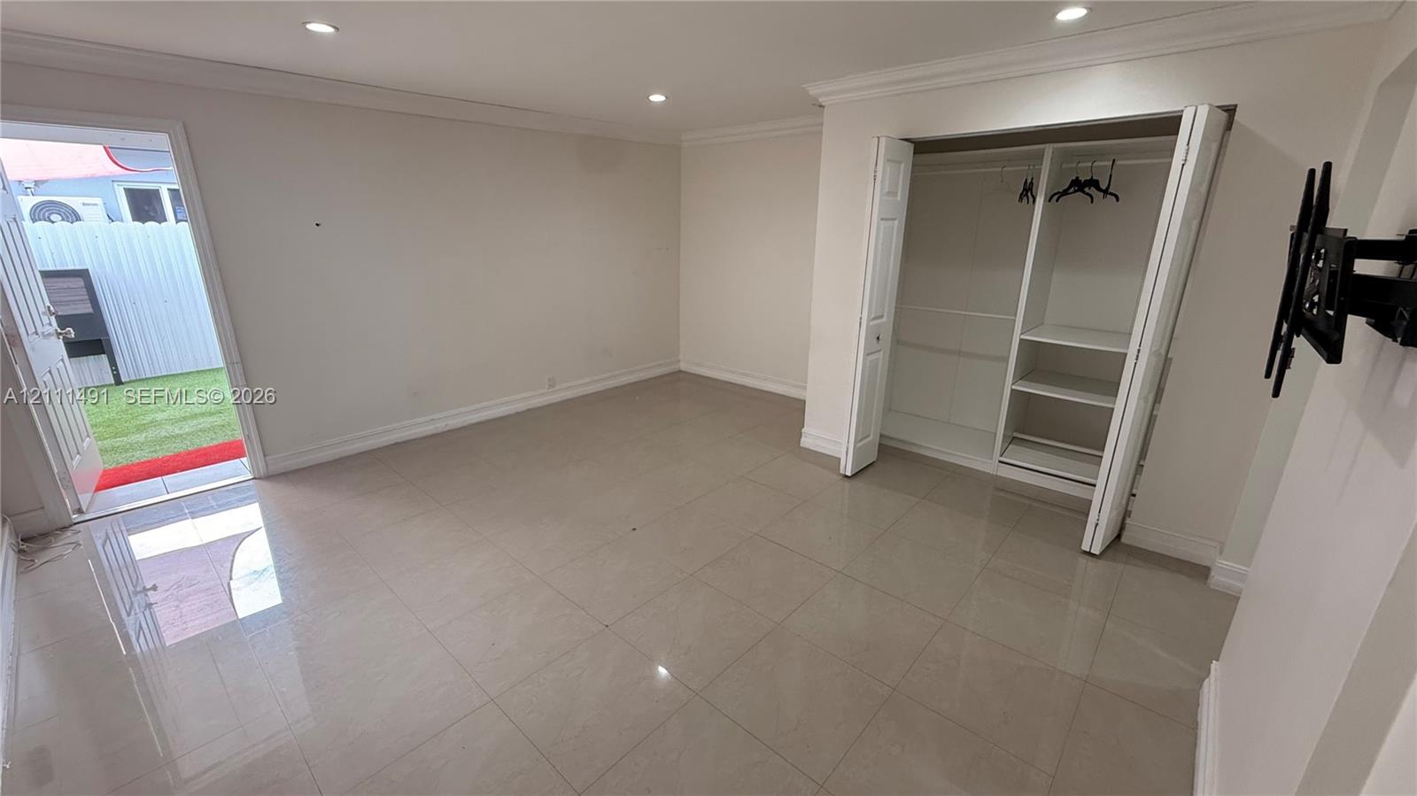 Interior space featuring large-format tile flooring, recessed lighting, and a closet with built-in shelving and dual-hinged doors