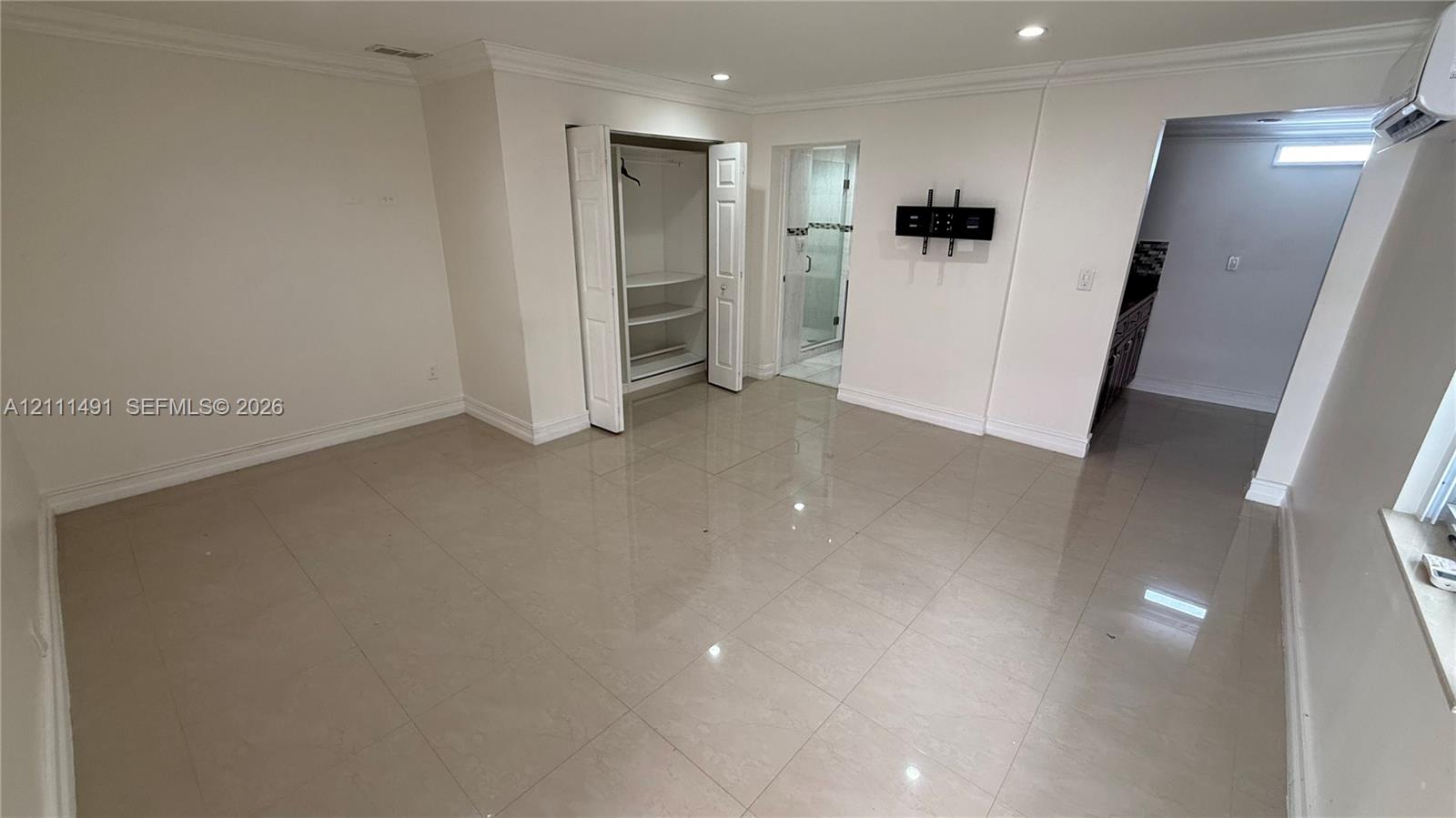 Polished tile flooring, recessed lighting, crown molding, built-in closet shelving, and a wall-mounted glass-enclosed shower