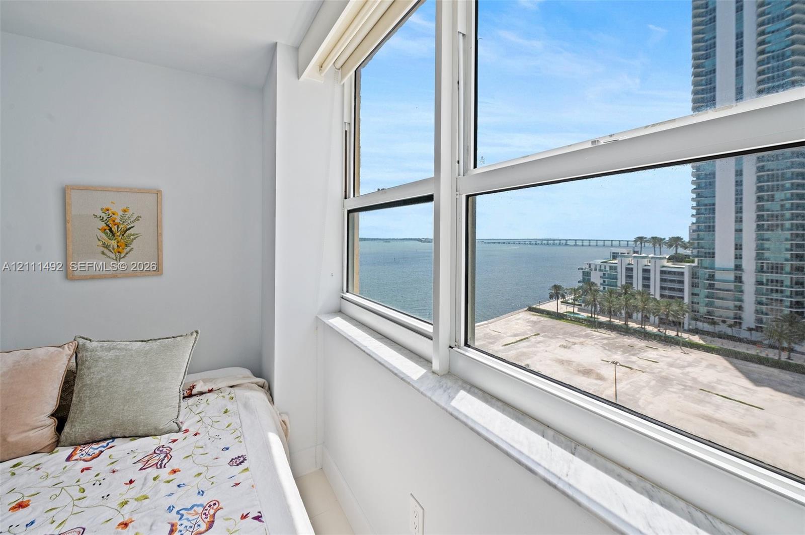Large multi-pane window with a stone sill, light-toned wall surfaces, and expansive water scenery