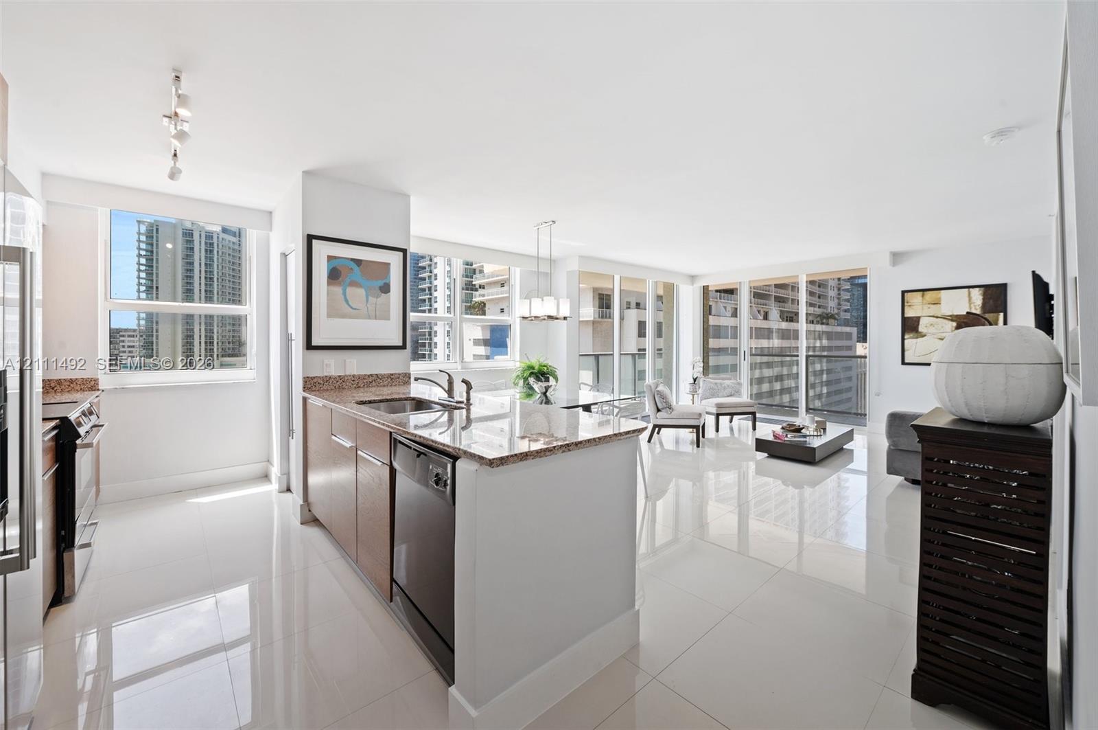 Kitchen featuring stone countertops, integrated stainless steel appliances, and wood-finish cabinetry, complemented by polished tile flooring and floor-to-ceiling windows