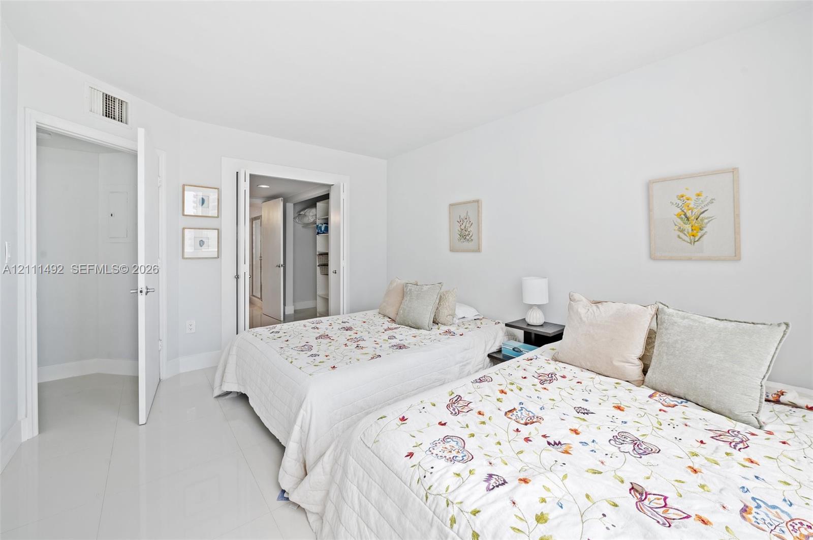 Bright interior featuring large-format tile flooring, double-door closet with built-in shelving, and neutral wall finishes