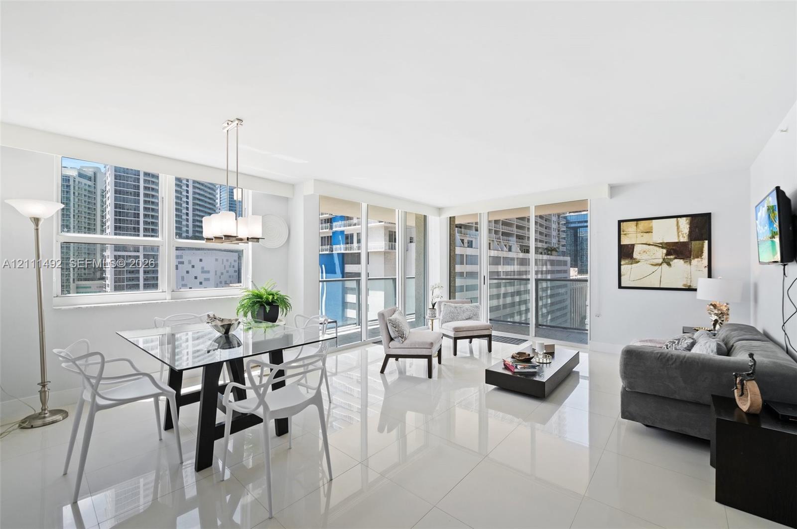 Open-concept main living area featuring floor-to-ceiling windows, polished stone tile flooring, and a glass-paneled balcony