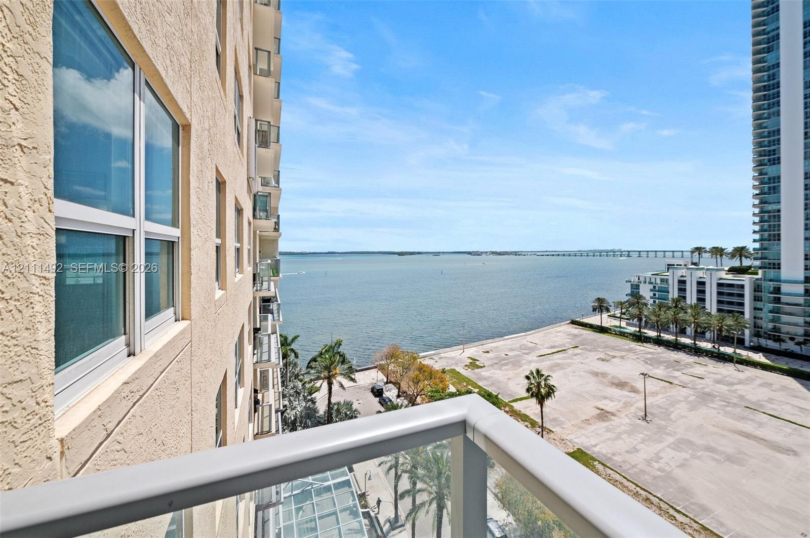 High-rise balcony featuring a metal-framed glass railing, textured exterior stucco finish, and expansive water expanse