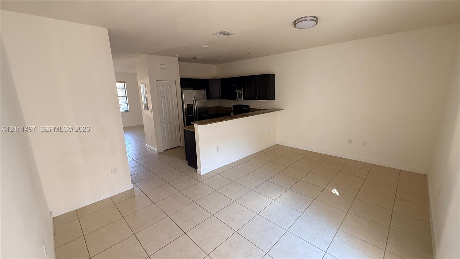 Kitchen featuring dark cabinetry, stone-finish countertops, stainless steel appliances, and tile flooring