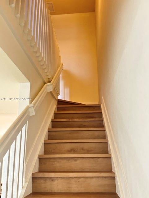 Staircase featuring wood-finish treads and white painted handrails with matching vertical balusters