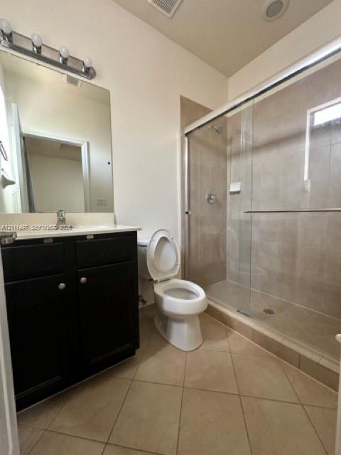 Dark wood-finish vanity with a light-toned countertop, glass-enclosed shower featuring neutral wall tile, and diagonal tile flooring