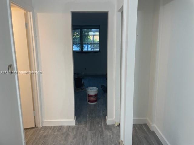 Interior hallway featuring white wall finishes and wood-finish flooring