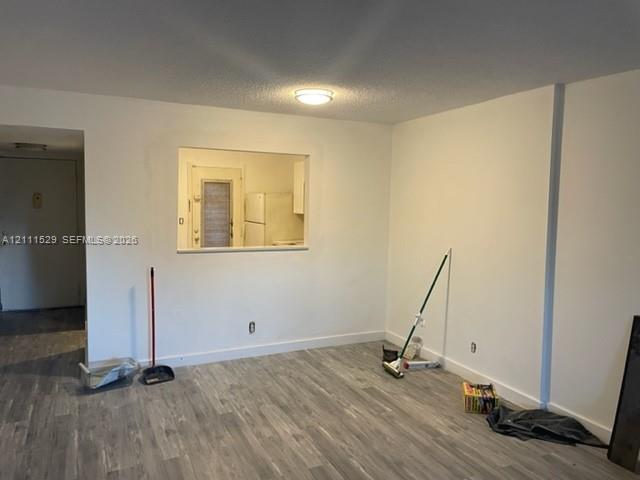 Open-concept interior featuring wood-finish flooring, neutral wall tones, and a pass-through window with a flush-mount ceiling light fixture